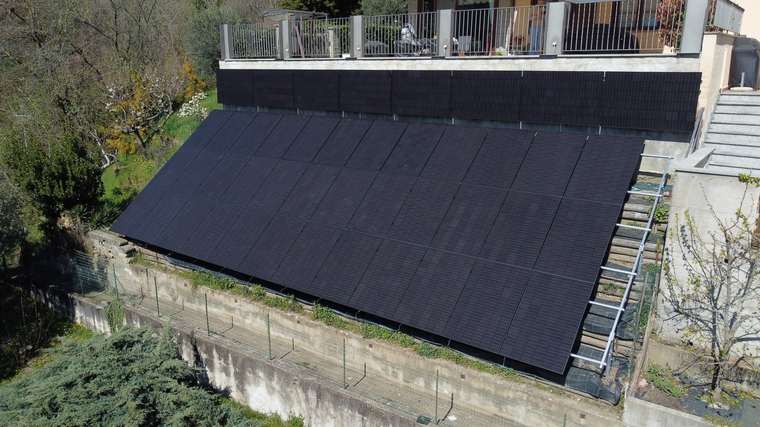 Realizzazione fotovoltaica iS ENERGY a San Pietro Val Lemina: Vista laterale dell impianto concluso, utile a leggere l inclinazione e il raccordo con scale e muri di contenimento.